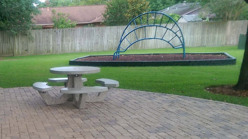 Fenced-in backyard with play area and concrete picnic table